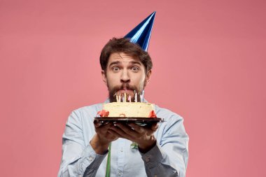 Pembe arka planda pasta dili olan sakallı bir adam. Kesilmiş bir manzara ve kafasında mavi bir şapka.