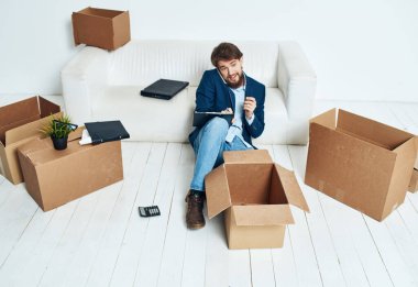Kutuların yanındaki işadamı eşyaların açıldığı yeni bir yere taşınıyor. Resmi yaşam tarzına.