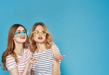 Çizgili tişörtlü iki kız kardeş iletişim duyguları mavi arka planda kavga ediyor