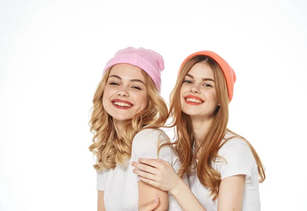 Alegre amigos do sexo feminino em chapéus multi-coloridos abraços estômago alegria luz fundo — Fotografia de Stock