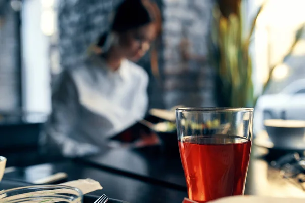 Mulher feliz na camisa e saia vermelha senta-se a uma mesa em um café com bloco de notas e caneta na mão — Fotografia de Stock