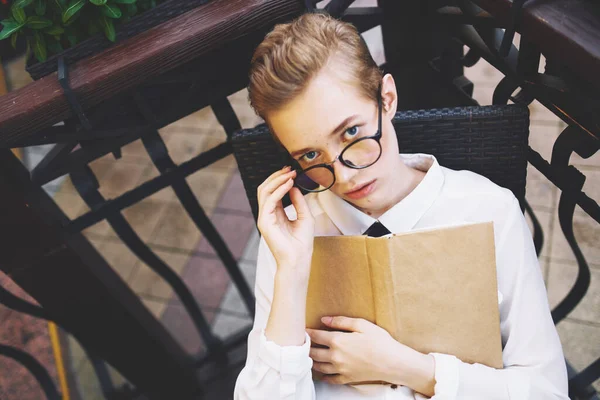 Trieste vrouw met kort haar zit in een stoel aan de cafe tafel emoties model boek — Stockfoto