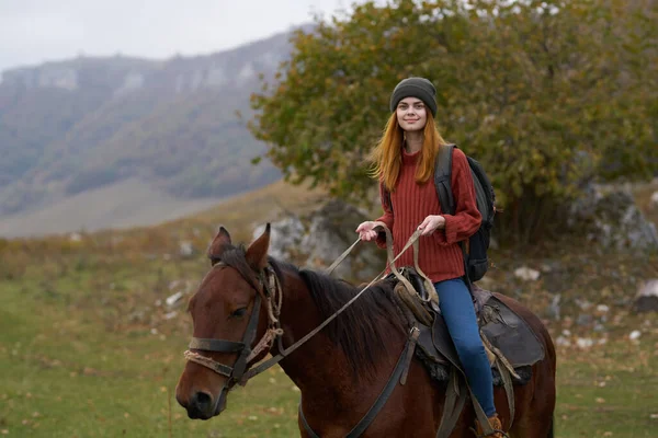 Mujer excursionista con una mochila monta un caballo en las montañas naturaleza viaje — Foto de Stock