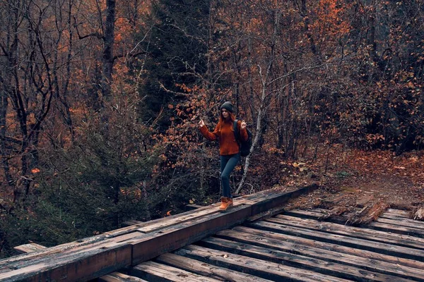 Kobieta turysta przecina most przez rzekę podróży jesienią — Zdjęcie stockowe