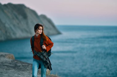 Sırt çantalı, kot pantolonlu bir kadın dağ manzarası modeli.