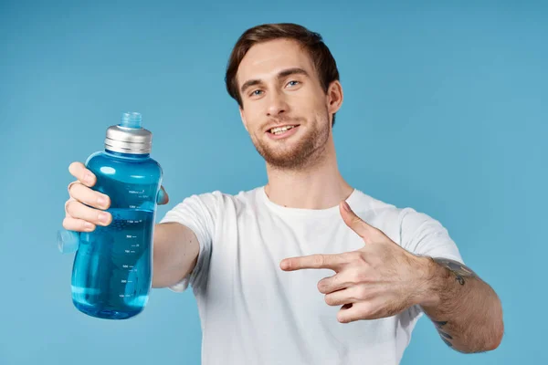 Uomo in bianco t-shirt bottiglia d'acqua dissetante vista ritagliata sfondo blu — Foto Stock