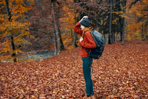 Happy travel vrouw met rugzak wandelingen door de herfst park in de natuur in de buurt van de rivier landschap hoge bomen trui — Stockfoto