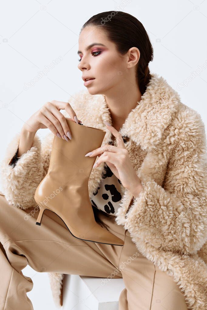 woman in fashionable clothes holding beige shoes in her hands