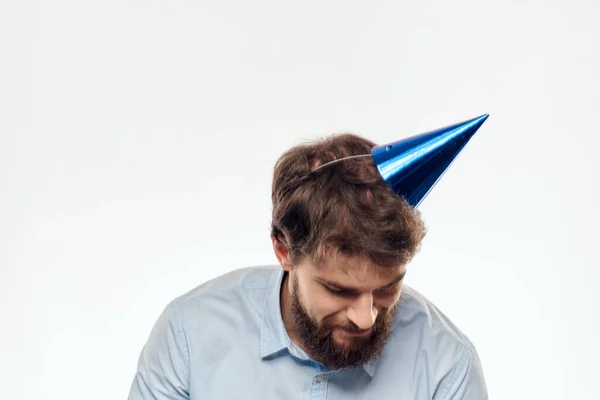 Un hombre celebra un cumpleaños sobre un fondo claro con un pastel en un plato gorra divertida flauta — Foto de Stock