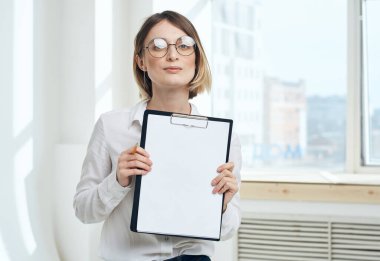 Pencerenin yanında doküman klasörlü kadın görüntüsü