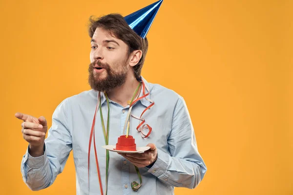 Cumpleaños niño en una gorra con un pastel de cumpleaños en la mano y una vela — Foto de Stock