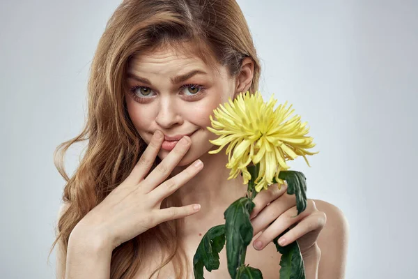 Portrait d'une belle femme avec une fleur jaune sur un fond clair charmant sourire modèle cheveux rouges — Photo