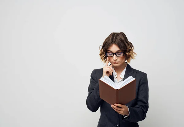 Business woman with a book in her hands on a light background Puzzled look Copy Space — Stock Photo, Image