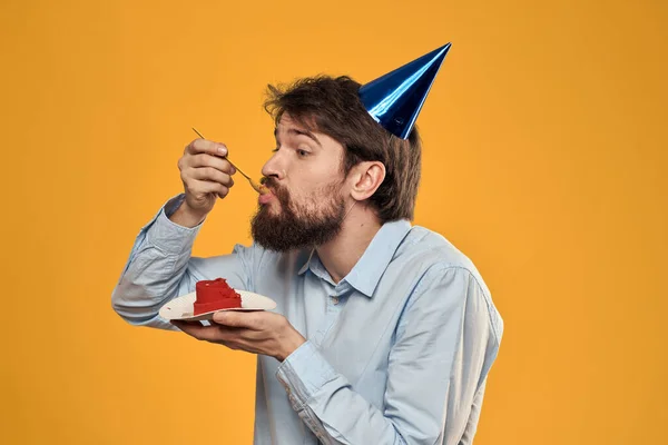 Hombre con pastel sobre fondo amarillo fiesta de cumpleaños sombrero vista recortada — Foto de Stock