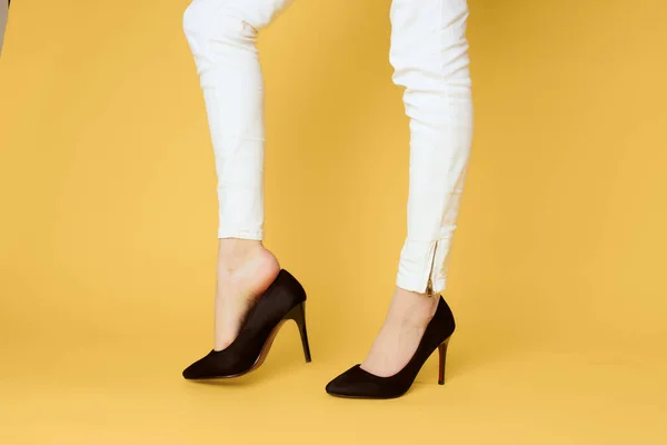 Pés femininos sapatos pretos moda roupas estúdio fundo amarelo — Fotografia de Stock