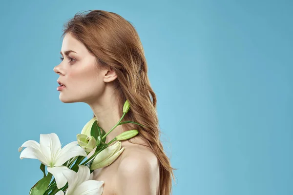 Žena s kyticí bílých květin na modrém pozadí nahá ramena krásná tvář — Stock fotografie