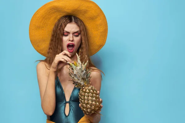 Kvinna i strand hatt ananas innehav baddräkt exotiska frukter blå bakgrund semester — Stockfoto