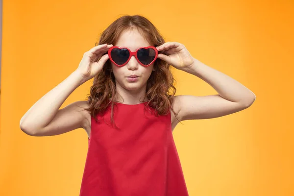 Дівчина в чорних окулярах червона сукня дитинства веселий жовтий фон — стокове фото