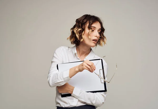 Geschäftsfrau mit einem Ordner mit Dokumenten in der Hand vor grauem Hintergrund. — Stockfoto