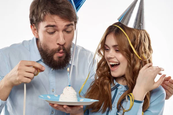 케이크를 들고 모자를 쓰고 밝은 배경에서 생일 을축하 하는 정력적 인 남녀 — 스톡 사진