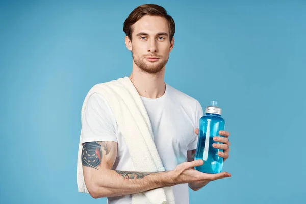 Uomo sportivo con tatuaggi sulle braccia bottiglia d'acqua blu allenamento — Foto Stock