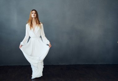 Gri arkaplan üzerinde beyaz elbiseli romantik kızıl saçlı kadın.