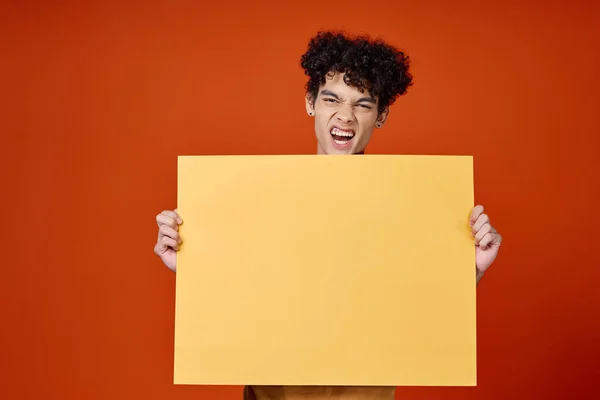 손에 곱슬머리노란 포스터를 들고 있는 감정적 인 남자 — 스톡 사진