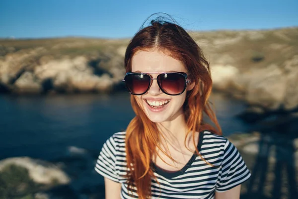 Retrato de um viajante feliz em uma camiseta e óculos e perto do mar nas montanhas — Fotografia de Stock