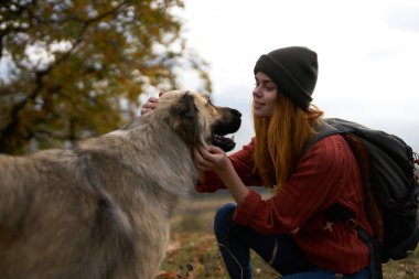 Bayan turistler dışarıda köpekle oynuyorlar. Arkadaşlık neşesiyle seyahat ediyorlar.