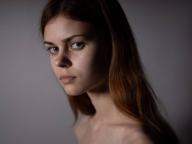 Kızıl saçlı, çıplak omuzlu, arka planda koyu renk, yakın plan portre.