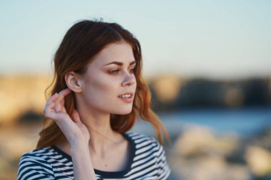 Doğada nehrin yanındaki dağlarda çizgili tişörtlü bir kadının portresi.