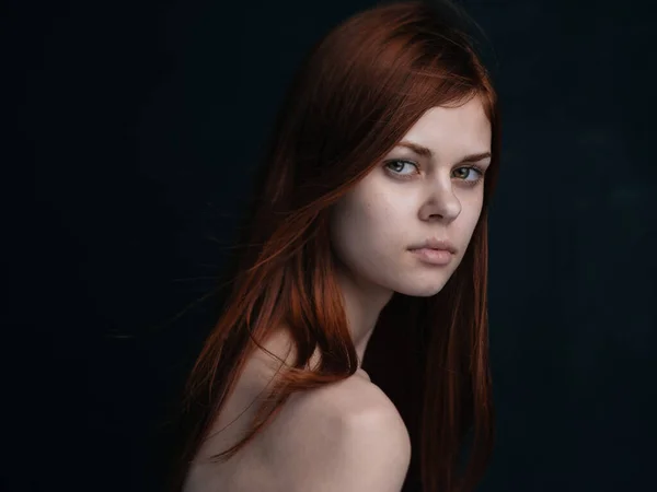 Retrato de uma mulher com cabelo vermelho em um fundo preto modelo de ombros nus — Fotografia de Stock