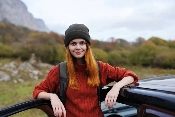 Kvinde vandrer med rygsæk nær bil på natur bjergtur - Stock-foto