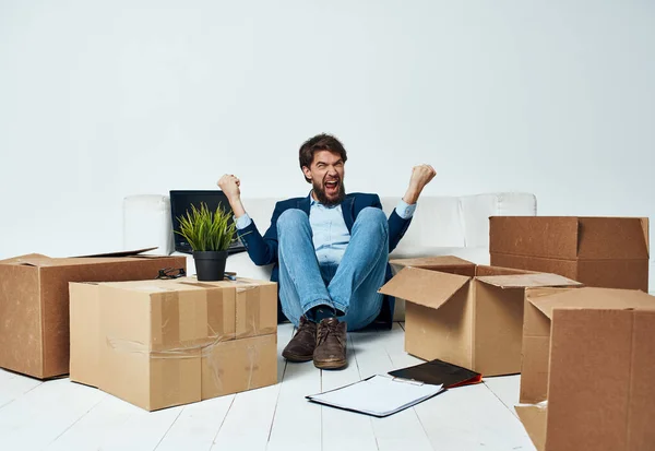 Man sitting on the floor with boxes of stuff moving to office unpacking lifestyle