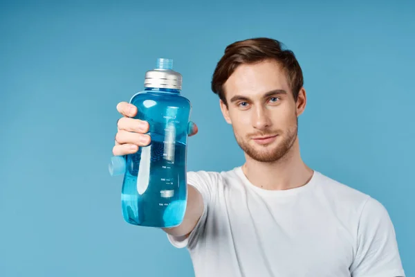 Hombre deportivo en camiseta blanca sosteniendo botella de agua azul en frente de él estudio — Foto de Stock