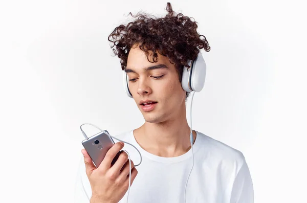 Τύπος με σγουρά μαλλιά σε λευκό μπλουζάκι ακούει μουσική τεχνολογία — Φωτογραφία Αρχείου