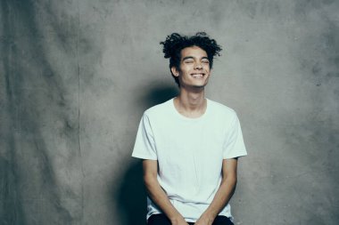 Tişörtlü, kıvırcık saçlı, yakın plan kumaşlı çekici bir adamın portresi.