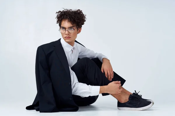 Hombre elegante con el pelo rizado en zapatillas de deporte sobre un fondo claro una chaqueta en el modelo de pantalones de hombro —  Fotos de Stock