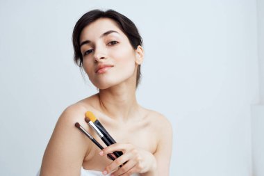 Güzel esmer, çıplak omuzlar makyaj fırçaları yakın plan makyaj malzemeleri.