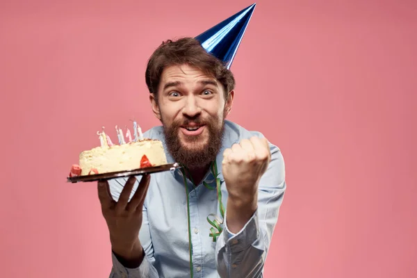 Hombre con pastel en un plato y en una camisa azul sobre un fondo rosa cumpleaños vacaciones vista recortada — Foto de Stock