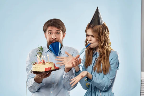 생일 파티 모자를 쓴 남자 파란색 배경에 촛불이 달린 케이크 — 스톡 사진