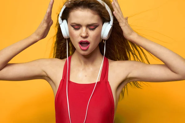 Mujer en auriculares escuchando música rojo camiseta emociones moda amarillo fondo estilo de vida —  Fotos de Stock