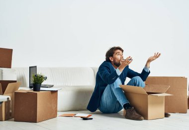 Bir adam, resmi bir işadamının duygularının açıldığı bir kutunun zemininde oturuyor.