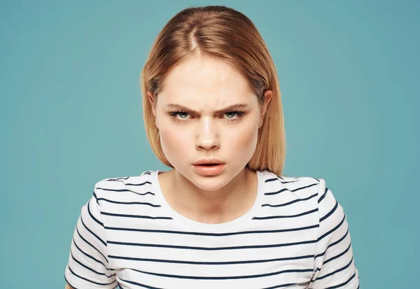 Porträt einer Frau auf blauem Hintergrund in gestreiftem T-Shirt erregt Irritation — Stockfoto