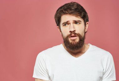 Pembe arka plandaki üzgün adam beyaz tişört ve çalı sakal manzarasını kesti.