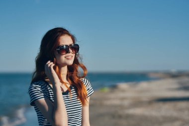 Kızıl saçlı güzel bir kadın yazın deniz kenarındaki kumsalda dinleniyor.