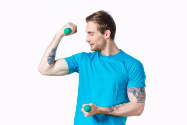 Elinde dambıllar, pompalanmış pazılarla egzersiz yapan bir adam.