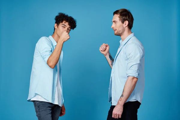 Ricci dai capelli ragazzo in una camicia saluta il suo amico su uno sfondo blu — Foto Stock