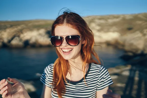 Portret szczęśliwego podróżnika w koszulce i okularach oraz w pobliżu morza w górach — Zdjęcie stockowe