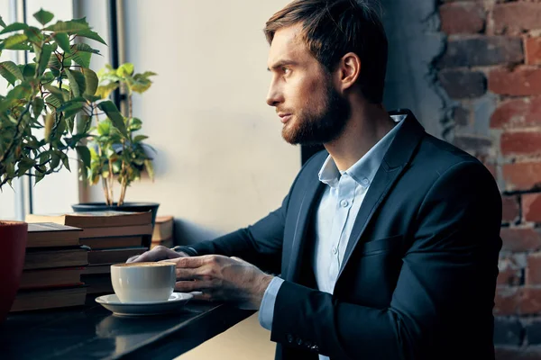 Homme d'affaires en costume assis à une table avec une tasse de café dans un café repos — Photo